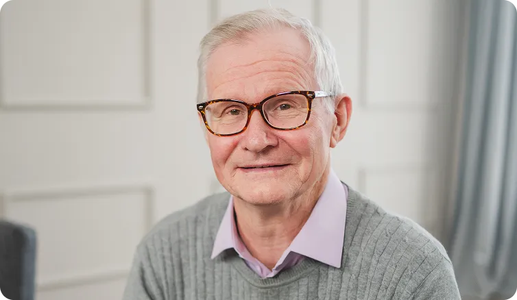 Confident senior man in glasses smiling – sharp everyday vision with cataract IOLs.